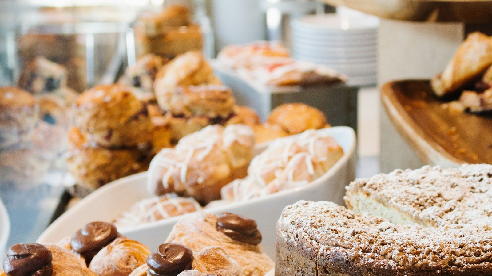 Trays of Italian pastries, filled swirl pastries and a crumb cake on display at a patisserie counter